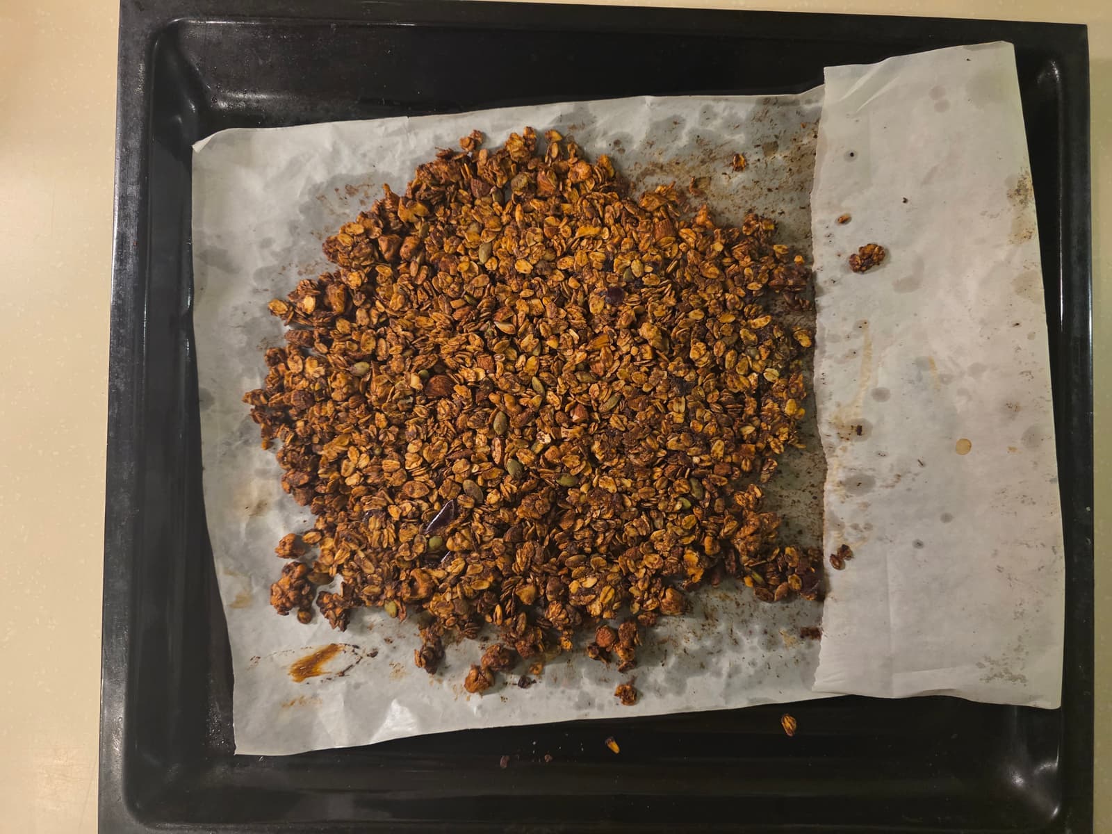 Top-down view of chocolate granola on a baking tray, fresh from the oven