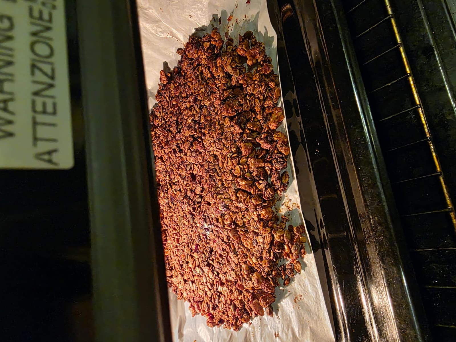 Chocolate granola baking inside the oven on parchment